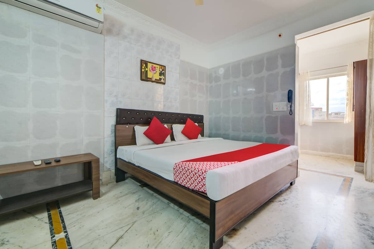 Um quarto com cama, mesa de cabeceira e janela.