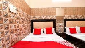 A hotel room with two beds, each with red and white bedding, and a red throw blanket. The walls are tiled with a mosaic pattern. - OYO 35497 Hotel Kapoor Residency (Amritsar)