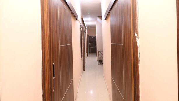 A narrow hallway with wooden doors on both sides, leading to a room at the end. - OYO 35497 Hotel Kapoor Residency (Amritsar)