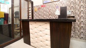 A reception desk with a patterned tile wall, a framed picture above, and a glass door to the left. - OYO 35497 Hotel Kapoor Residency (Amritsar)