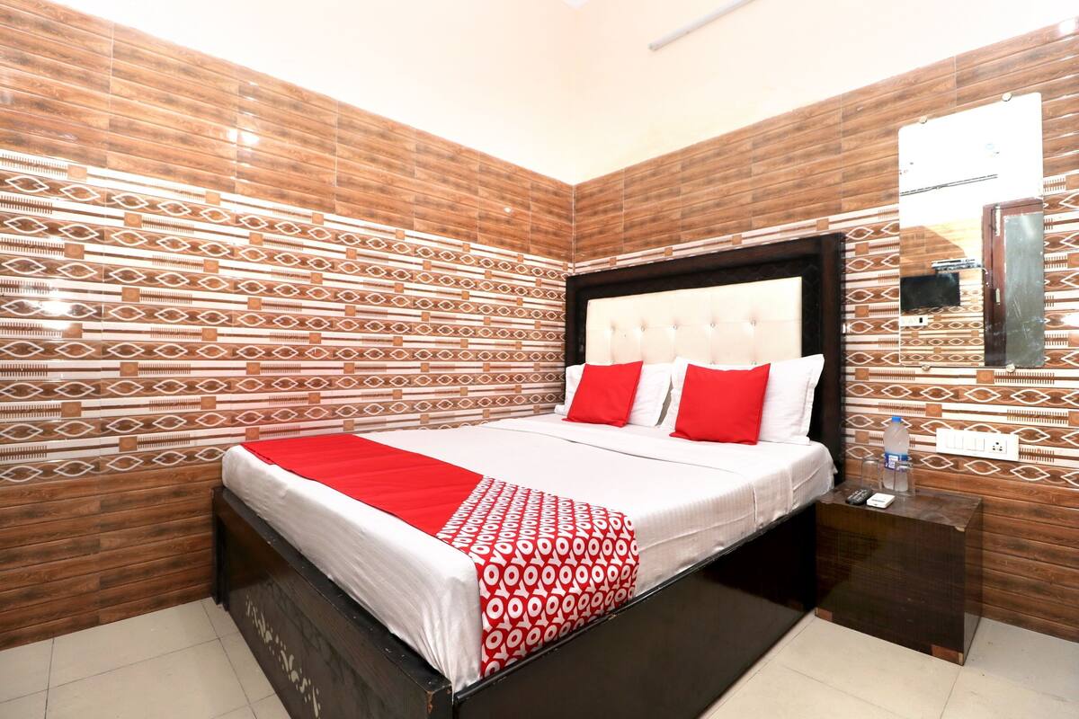 Ein ordentlich eingerichtetes Hotelzimmer mit Bett, Nachttisch und einem an der Wand befestigten Spiegel.