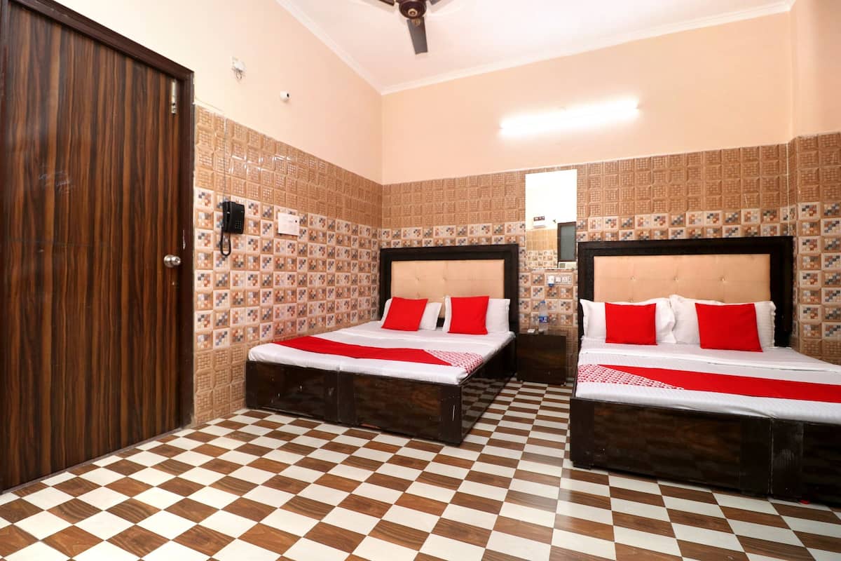 Ein Hotelzimmer mit zwei Betten, einem Schachbrettmuster-Boden, gemusterten Wänden und einer Holztür.