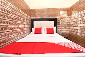 Een hotelkamer met een bed, rode en witte beddengoed en behang met een patroon.