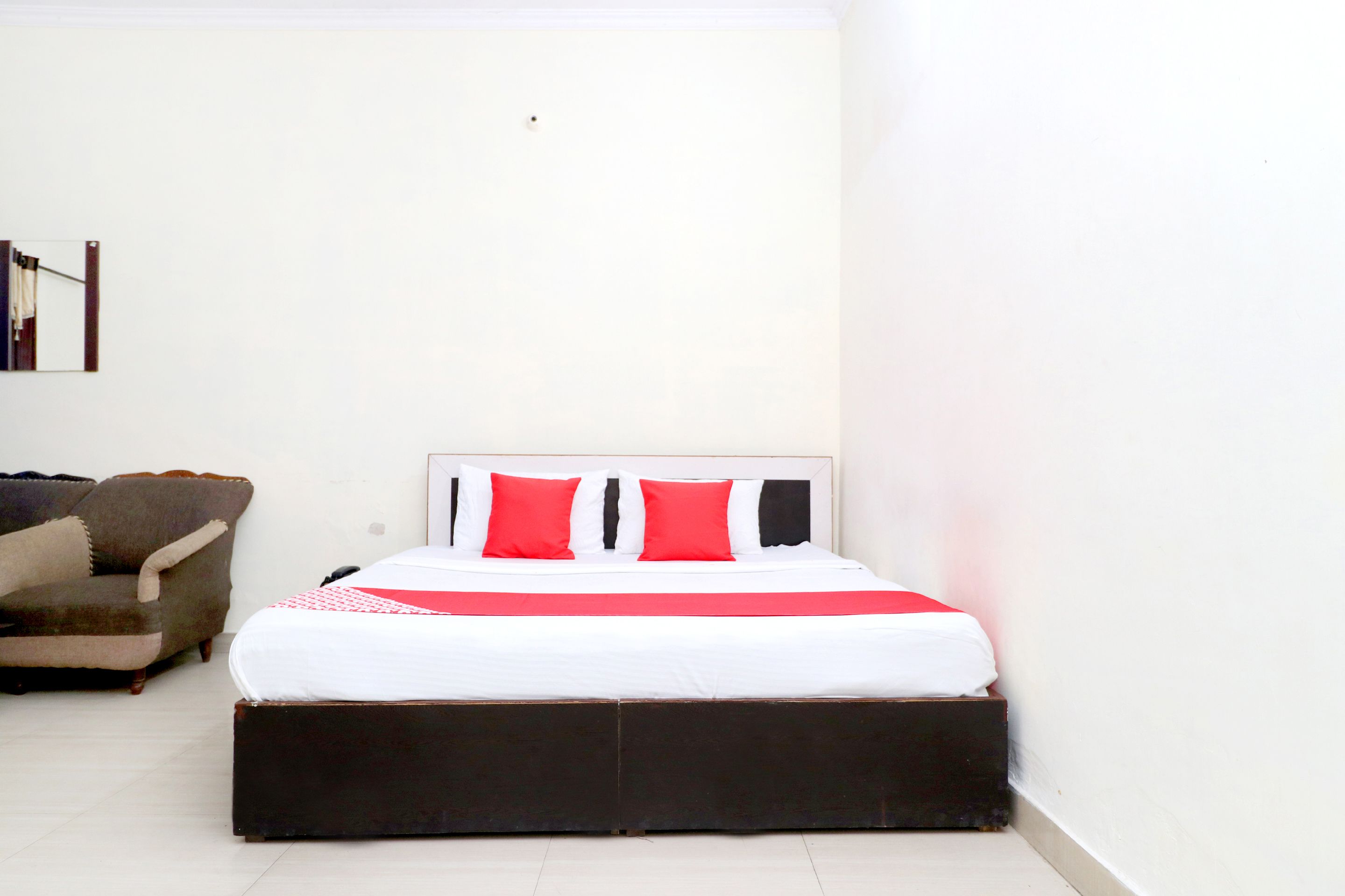 A bedroom with a bed, a chair, and a mirror on the wall.
