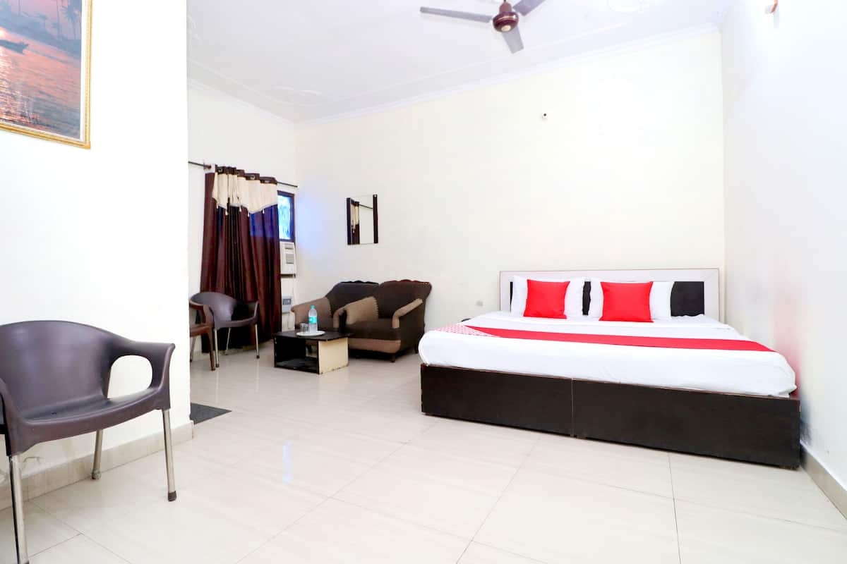 A bedroom with a bed, a chair, a sofa, and a desk.