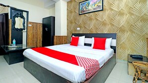 Ein Hotelzimmer mit einem großen Bett, einem Holzschrank, einem Spiegel und einem Gemälde an der Wand.