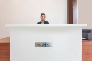 A reception desk with a sign that reads "RECEPTION" and a person standing behind it. - Collection O 23058 Hotel Aditya Regency (Bhopal)