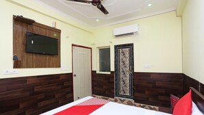 Une chambre d’hôtel équipée d’un lit, d’un téléviseur fixé au mur, d’un climatiseur et d’un ventilateur de plafond.