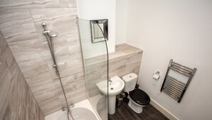 A modern bathroom with a glass-enclosed shower, a pedestal sink, and a toilet. - Cross St Boutique Apartment (Altrincham)