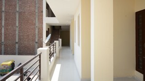 A corridor with a staircase, a balcony, and a brick wall. - OYO 37658 King Palace (Mohali)