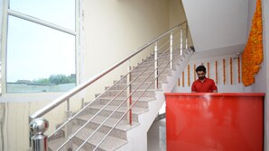 A staircase with a metal handrail and a red reception desk with a decorative garland. - OYO 37658 King Palace (Mohali)