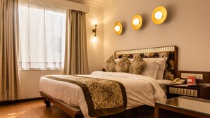 Ein Hotelzimmer mit einem großen Bett, einem Nachttisch mit Lampe und einem Fenster mit Vorhängen.