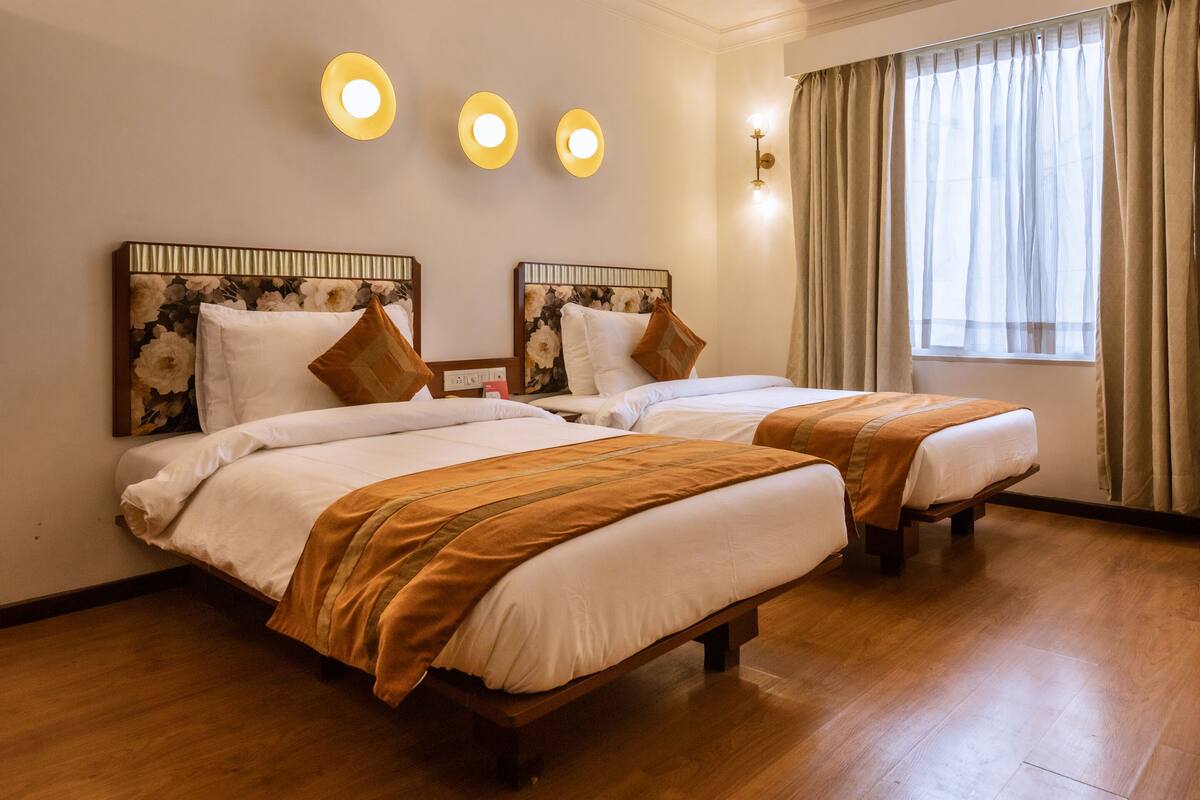 A hotel room with two beds, wooden headboards, and a large window with curtains.