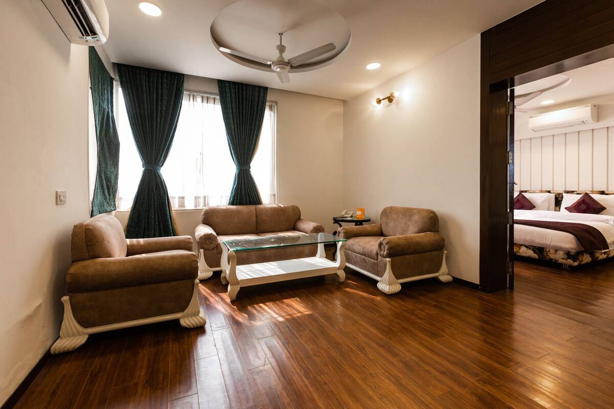 A modern living room with a glass coffee table, two brown armchairs, and a sofa.