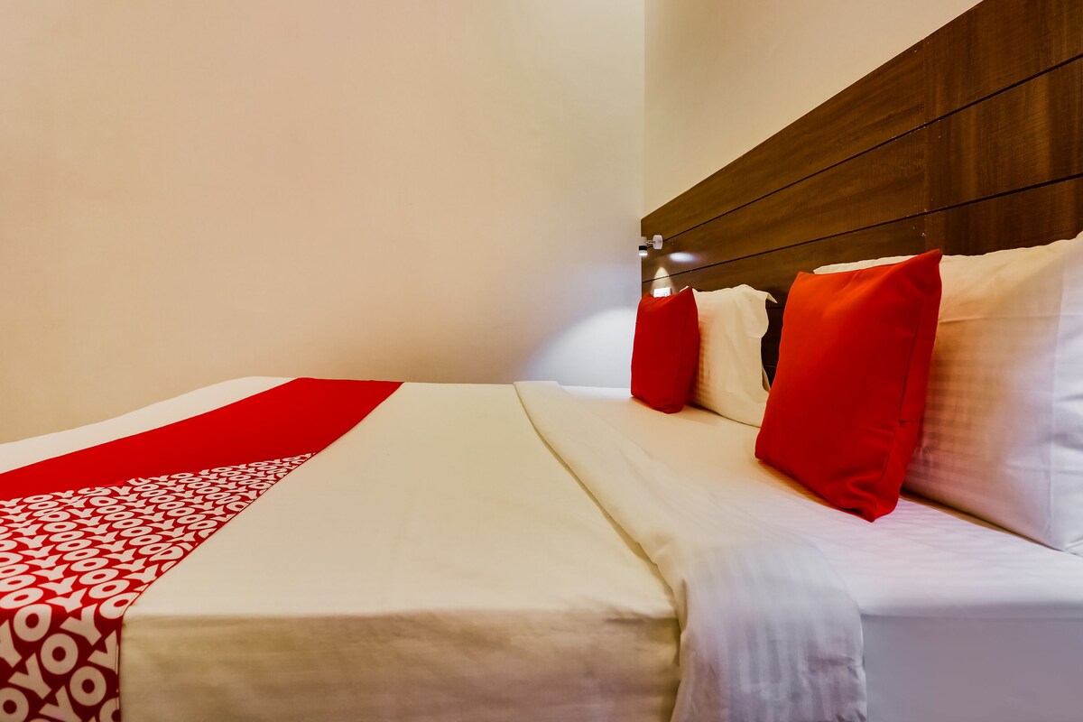 A neatly made bed with white and red bedding, a wooden headboard, and a red and white patterned runner.