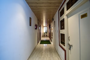 A hallway with a wooden ceiling, a green mat, and a door marked with the number 305. - OYO 35374 Hotel Kanchan Residency (Kota)