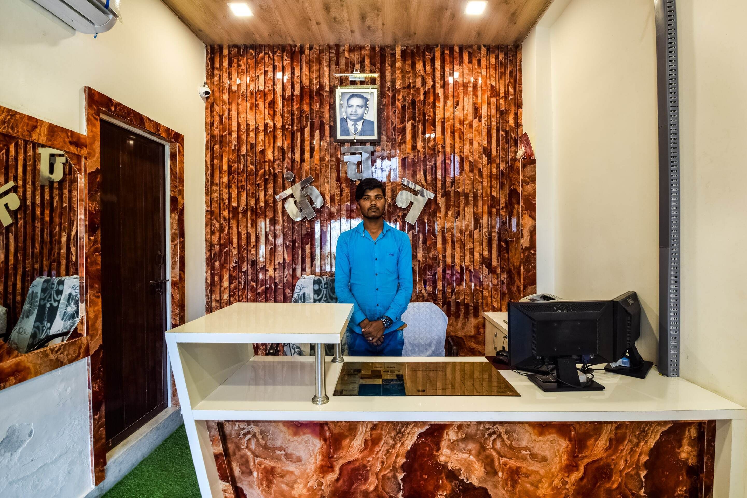 A reception desk with a marble-like wall, a framed photograph above it, and a computer monitor to the right.
