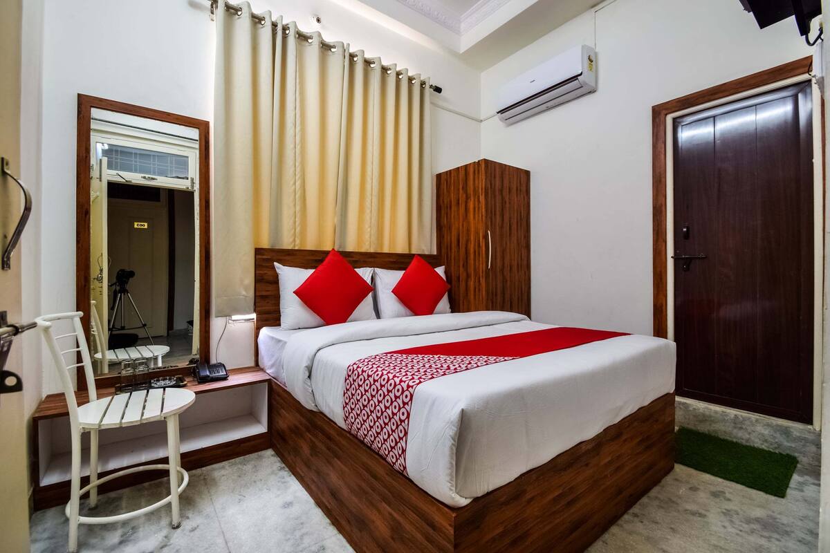 A neatly arranged bedroom with a bed, a desk, a chair, a wardrobe, and a door.