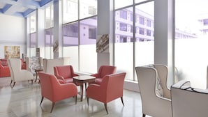 A spacious lobby with large windows, modern furniture, and a view of a building outside. - Capital O 44162 Royal Palms Hotel - Rose Collection (Mumbai)