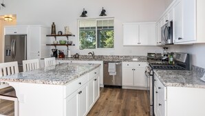 Eine moderne Küche mit weißen Schränken, Granit Arbeitsplatten, einem integrierten Geschirrspüler und einem Edelstahlkühlschrank.