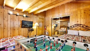 A cozy room with wooden walls, a foosball table, a bed, and a television. - Oriole Cottage #621 (Big Bear Lake)