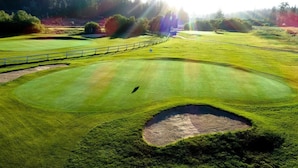 A golf course with multiple putting greens, sand bunkers, and a white fence. - Bear Mountain Chalet #639 (Big Bear Lake)