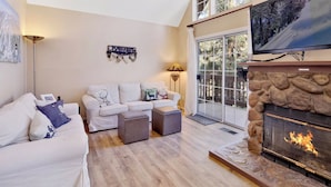 A living room with a fireplace, a sofa set, a television, and a large window. - Bear Mountain Chalet #639 (Big Bear Lake)