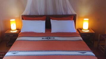 A bed with a canopy, two bedside lamps, and a patterned bedspread.