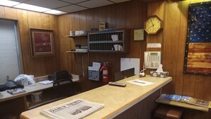 Un comptoir d’accueil avec une horloge, un extincteur et un calendrier accroché au mur.