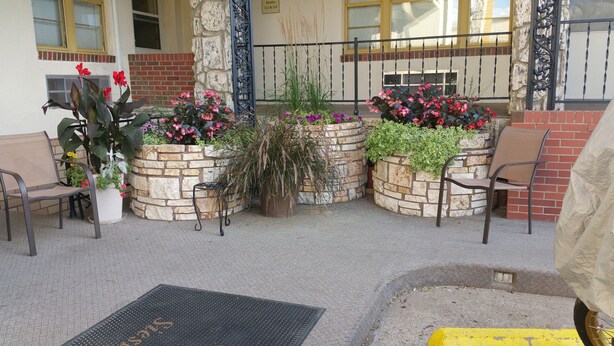 L’entrée d’un hôtel, agrémentée de jardinières en pierre, de bancs et d’un portail en métal.