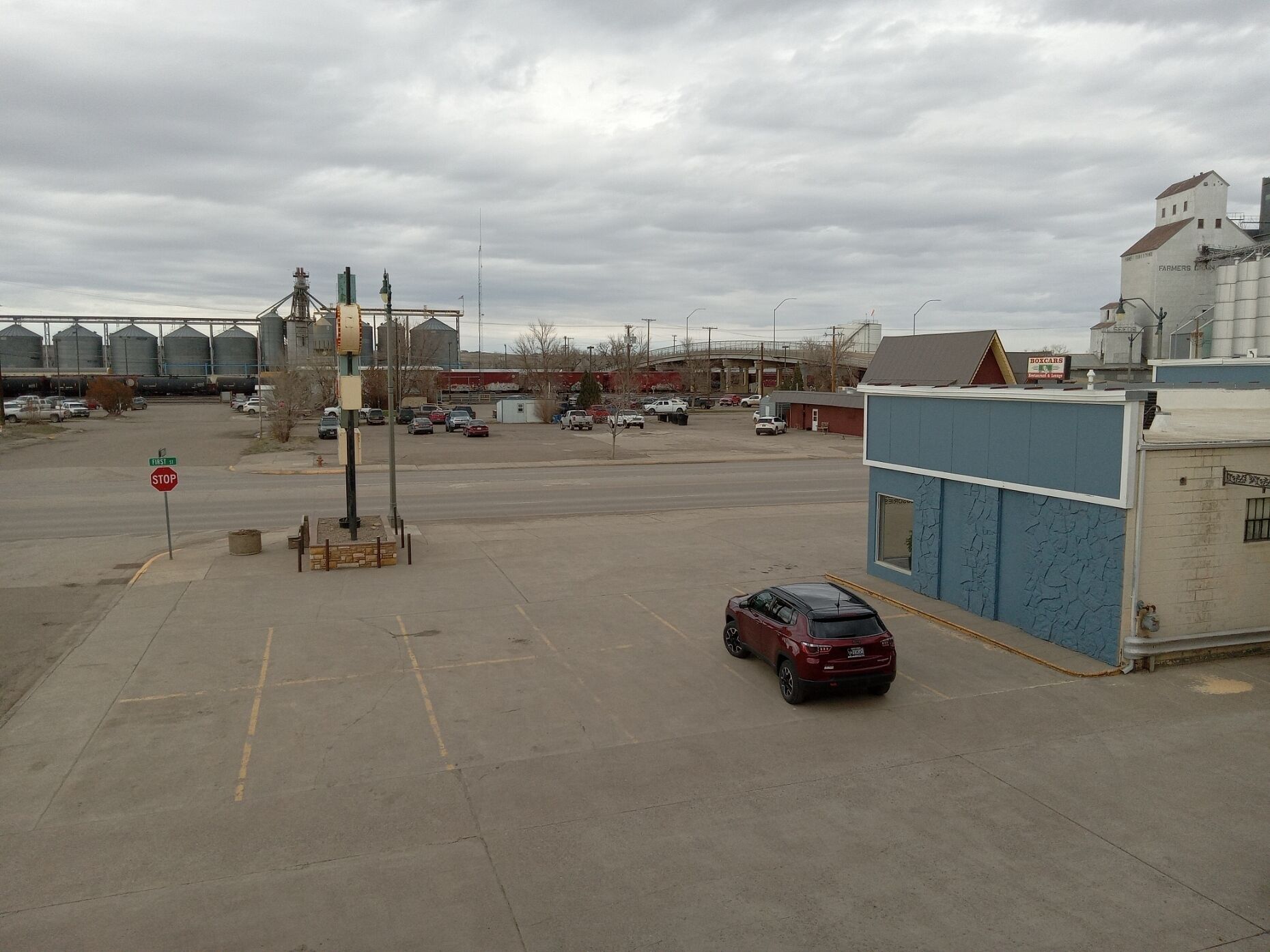 A parking lot with a red car parked near a blue building with a sign that reads "Boxcar."