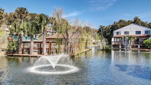 Un lago tranquilo con una fuente, rodeado de palmeras y edificios residenciales.