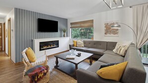 Una sala de estar moderna con chimenea, un sofá, una mesa de centro y un televisor montado en la pared.