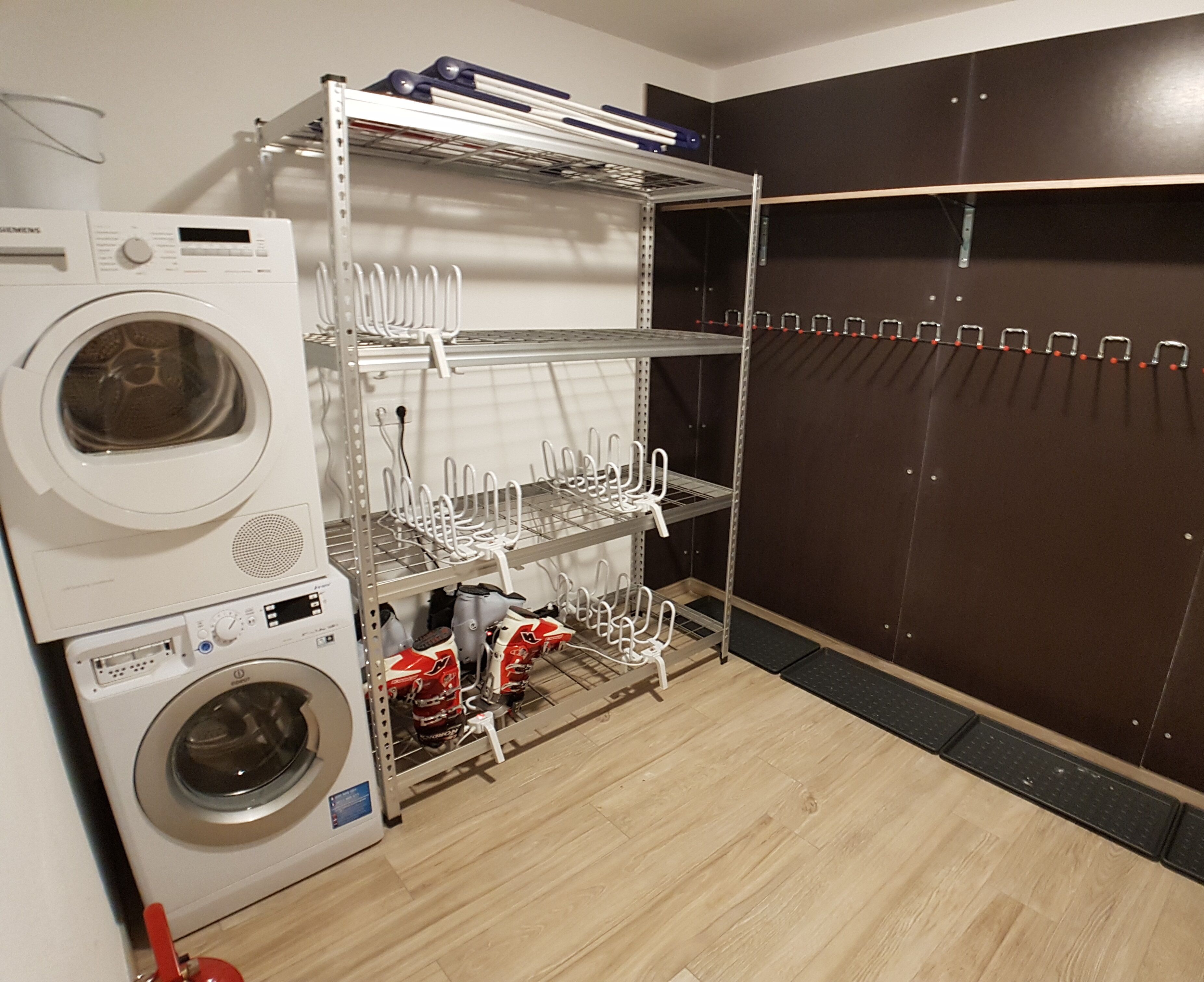 A laundry area with a washing machine and dryer, shelves for hanging clothes, and a storage closet.