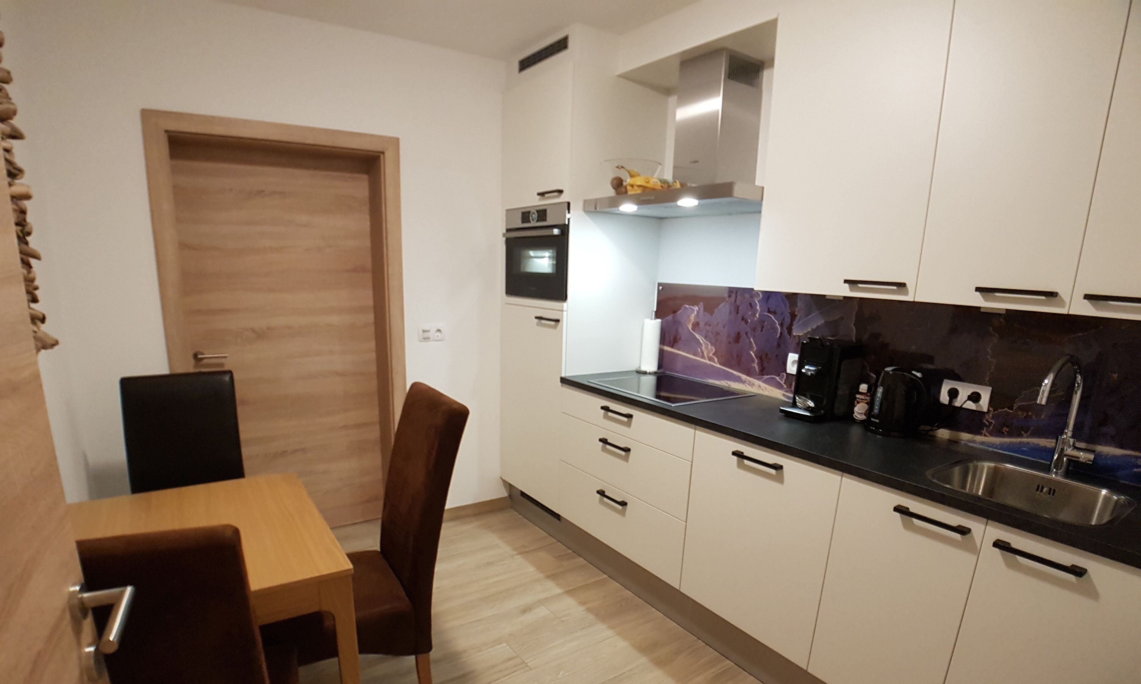 Una cocina compacta con una mesa de comedor de madera, una silla y un horno empotrado.
