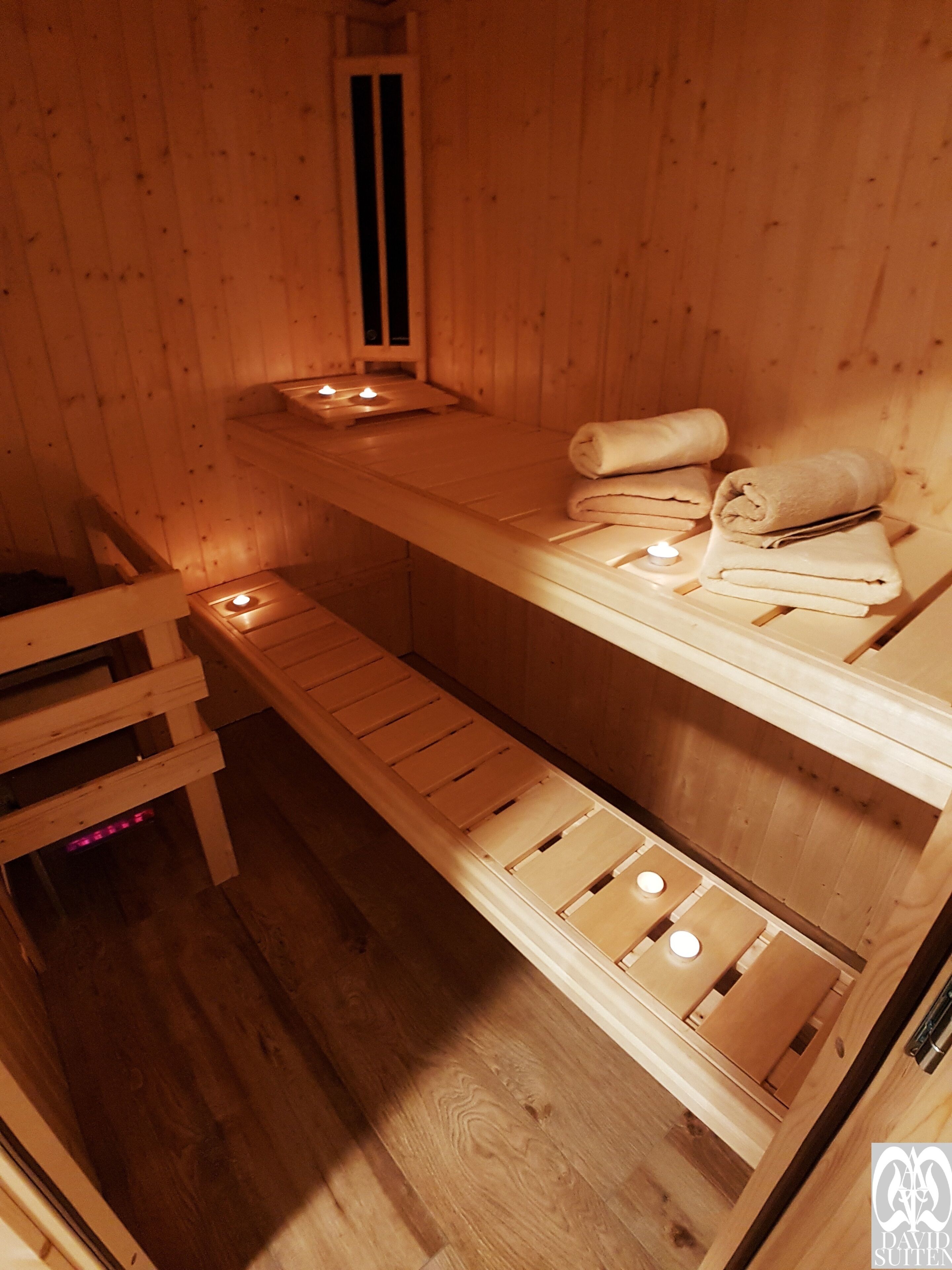 A wooden sauna with benches and a shelf for towels.