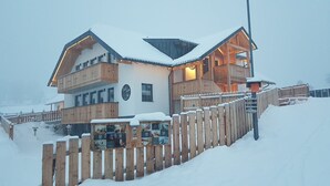A two-story wooden chalet with a balcony, a sign reading "Hotel", and a wooden fence in front. - David Suiten (Mauterndorf)