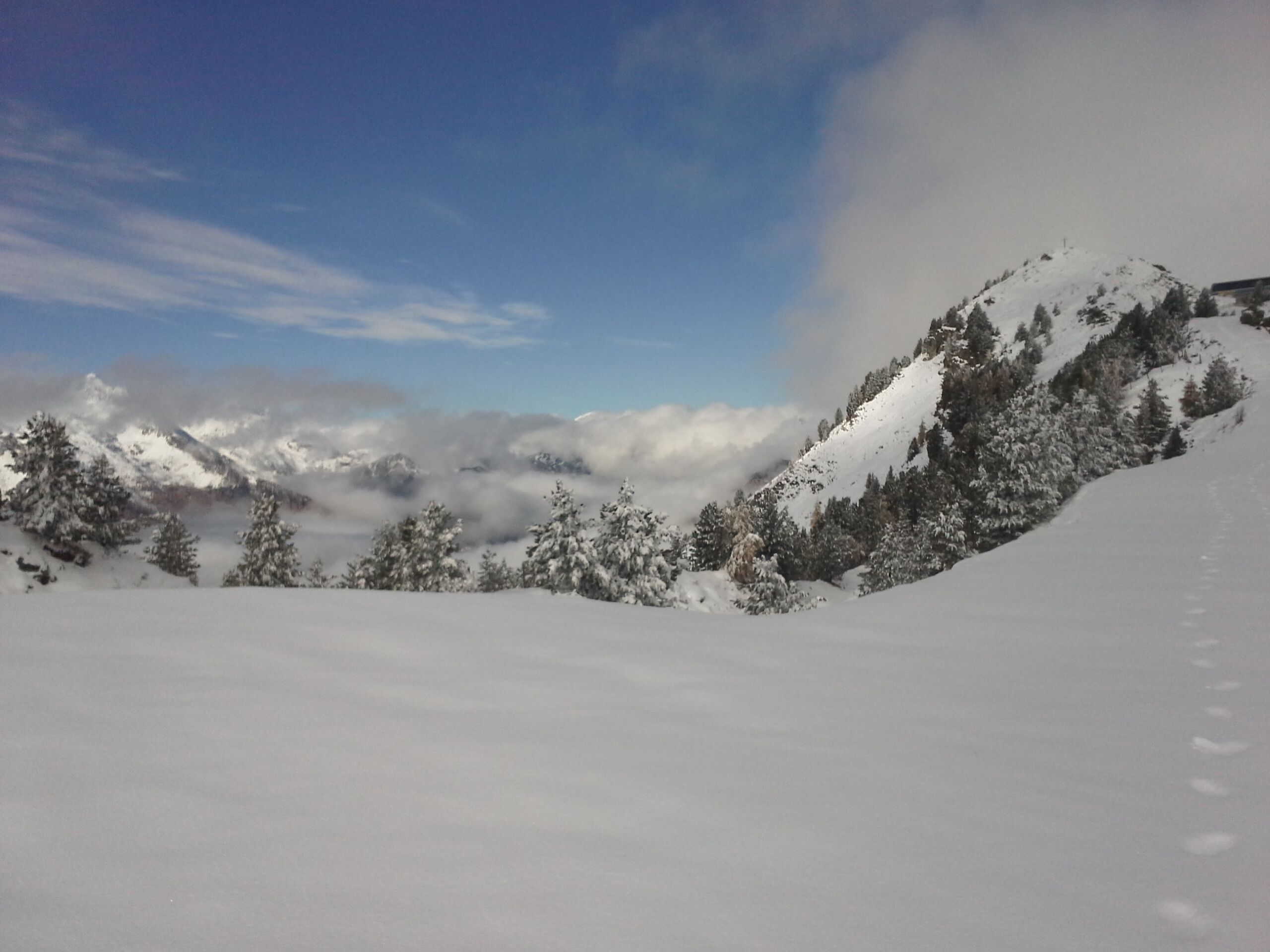 A snowy mountain landscape with trees and a clear sky.