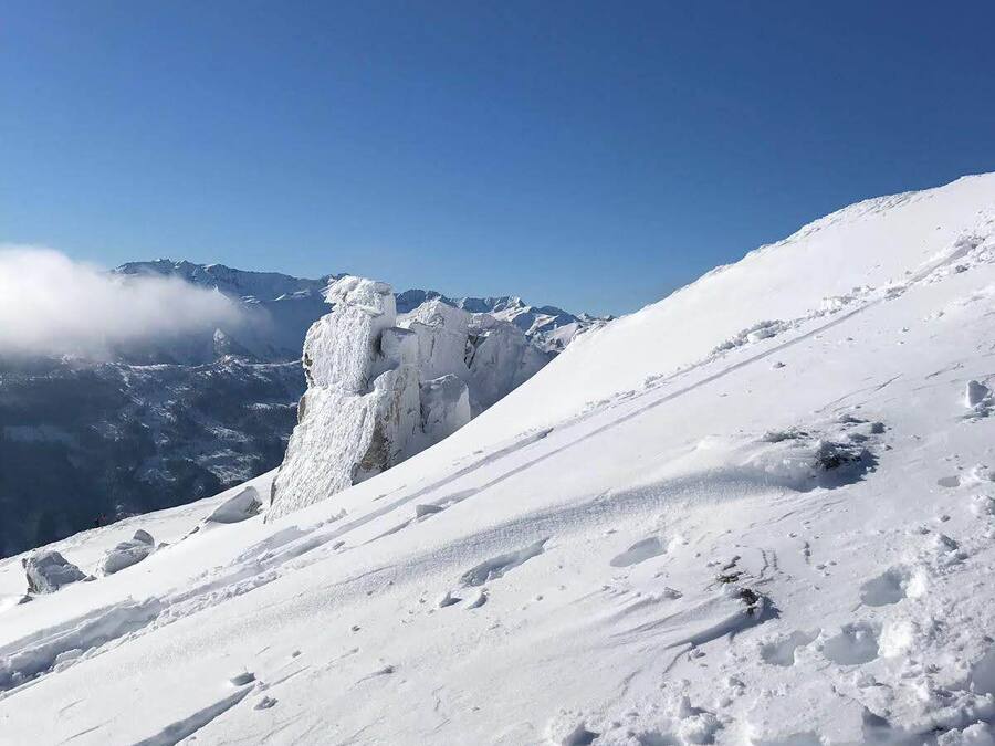 A snow-covered mountain slope with a clear sky.