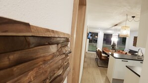 A modern kitchen with a wooden accent wall, a dining area with a Christmas tree, and a view of the outside. - David Suiten (Mauterndorf)