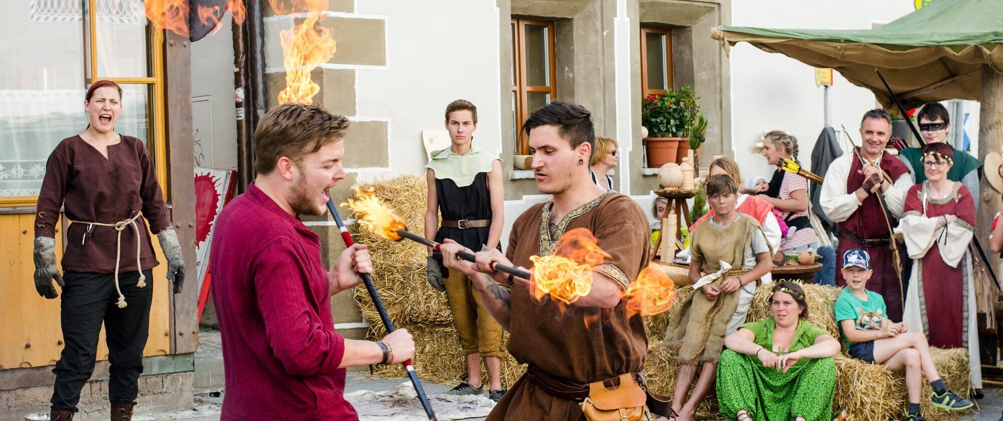 A group of people in historical costumes with torches, suggesting a themed event or reenactment.