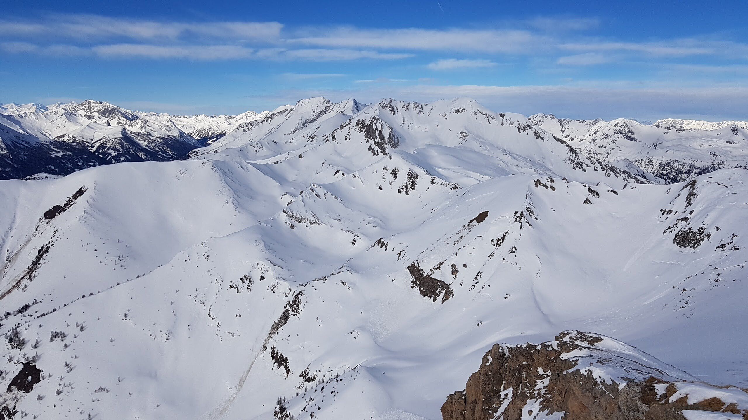 A snow-covered mountain range with rugged terrain and clear skies.