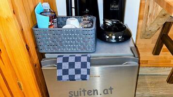 A stainless steel refrigerator with a checkered towel on it and a basket of items on top.