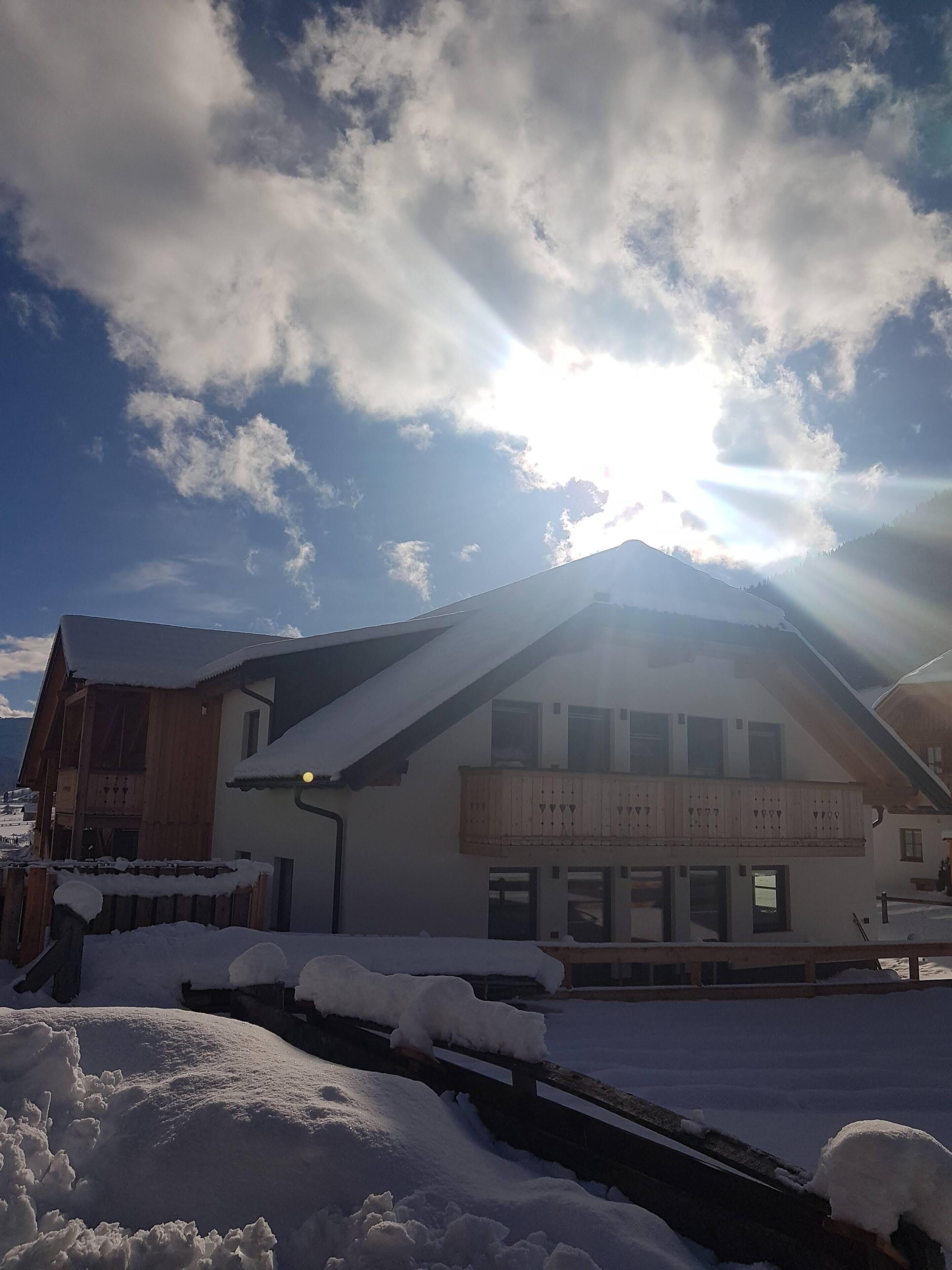Ein mit Schnee bedecktes Gebäude mit einem geneigten Dach und einem Balkon.