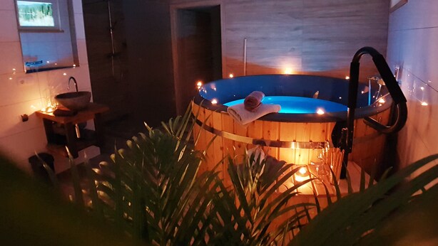 A spa area with a wooden hot tub, a sink, and a mirror. - David Suiten (Mauterndorf)