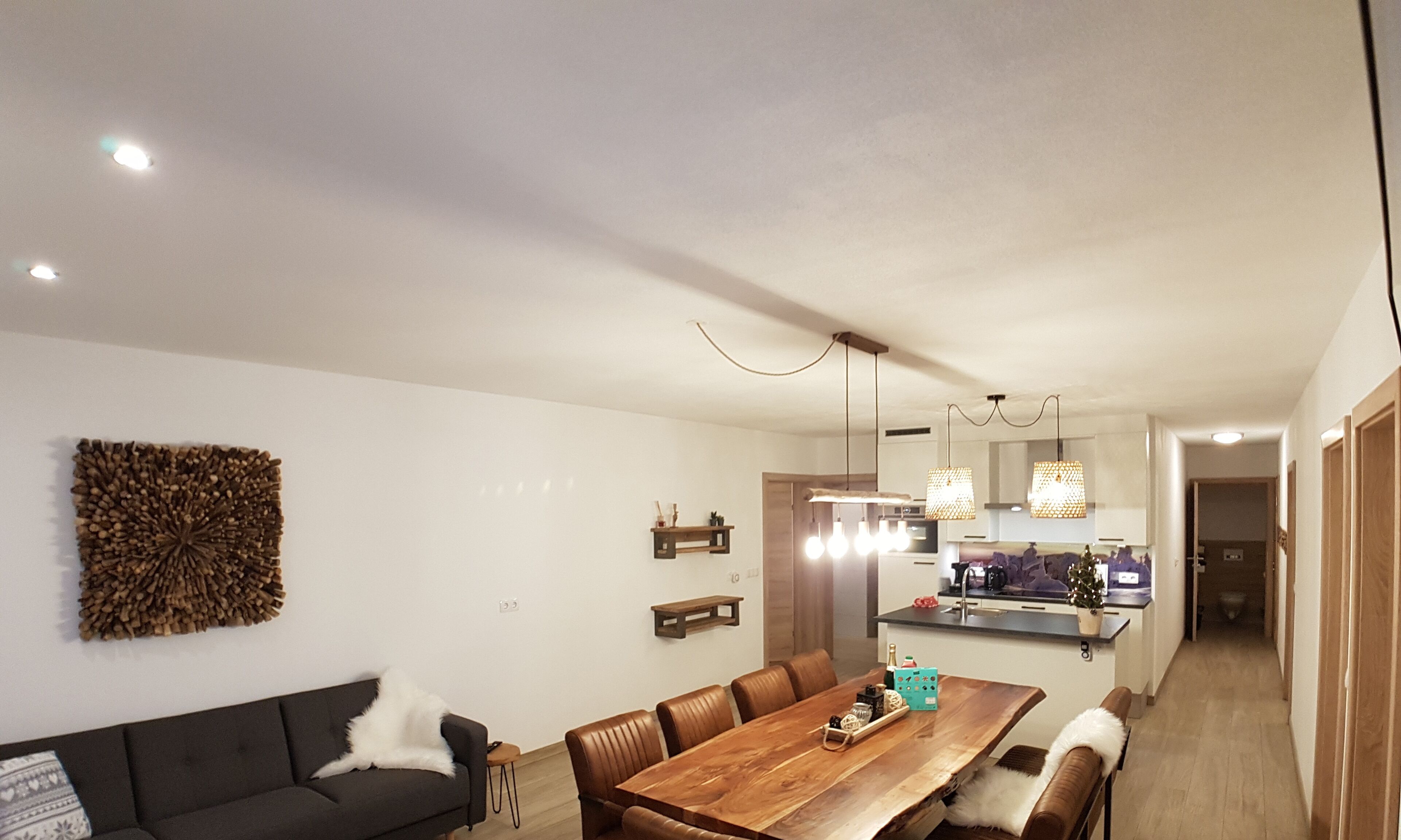 A modern kitchen with a wooden countertop, hanging pendant lights, and a built-in oven.