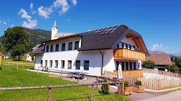 Un edificio de dos pisos con techo inclinado, paneles solares y un balcón.