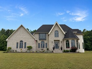 A two-story house with a brick facade, a front porch, and a well-maintained lawn. - Spacious Pet Friendly ($) Home w/Game & Exercise Room (Harbor Springs)