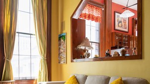 A cozy living room with a sofa, a blue patterned rug, and a large window with curtains.