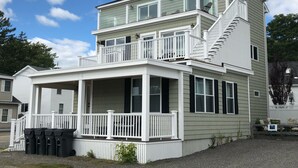 Ein zweistöckiges Haus mit Balkon, einer Veranda und einer Treppe, die zu der oberen Etage führt.